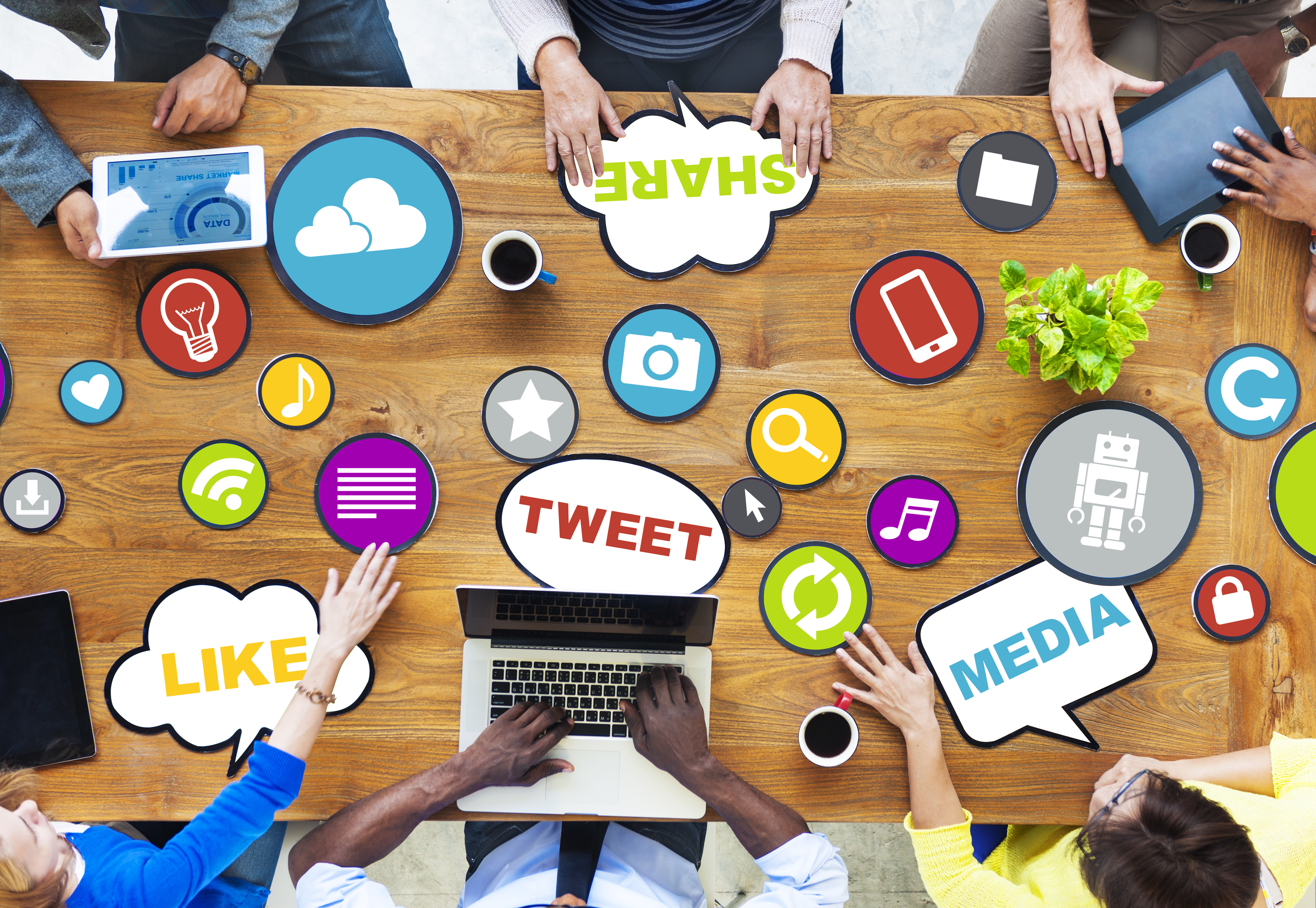 Overhead view of 6 people sitting at a desk sharing ideas about social media